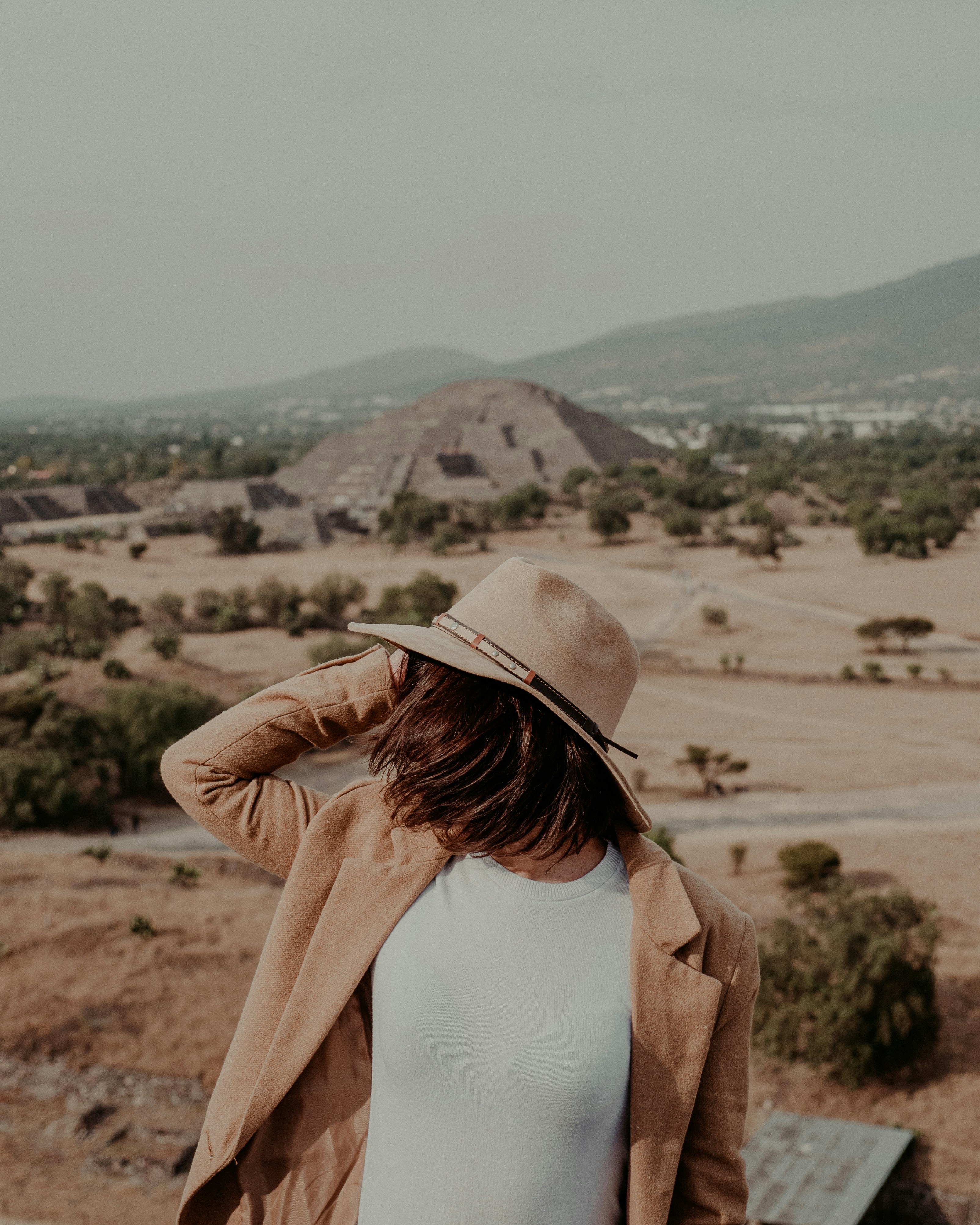 woman-in-white-tank-top-and-brown-cardigan-standing-on-brown-field-during-daytime