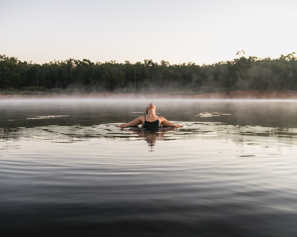 woman in black bikini on body of water during daytime