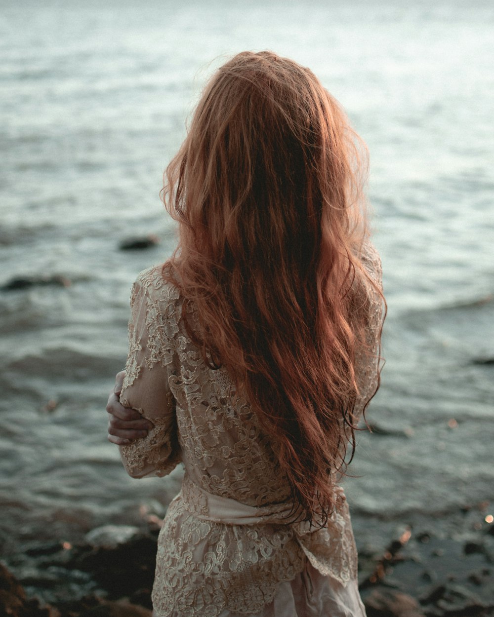 woman in white lace long sleeve shirt standing on seashore during daytime