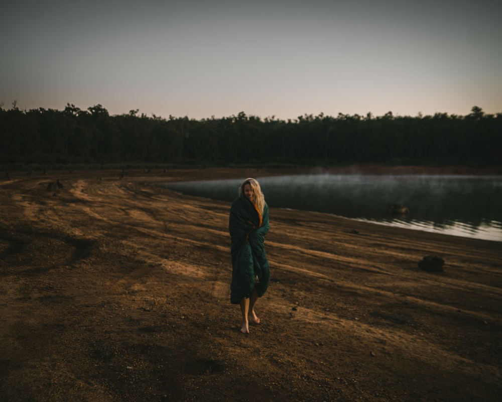 woman in green jacket standing on brown field during daytime