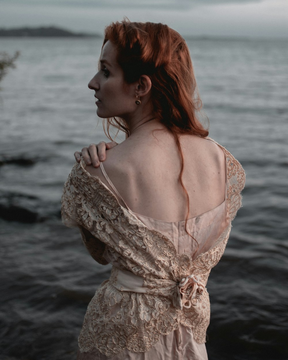 woman in white floral dress standing on sea shore during daytime