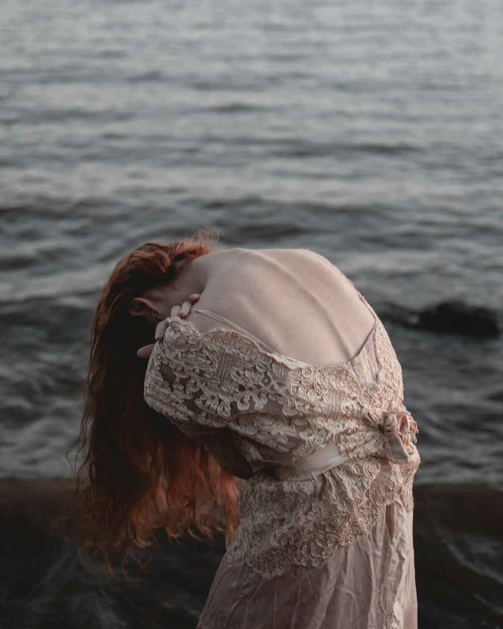 woman in white lace floral lace top standing on seashore during daytime