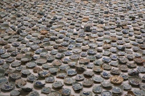 Close-up of colorful broken ceramic pieces arranged like a mosaic on a wooden table.
