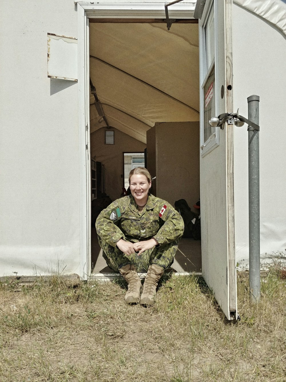 man in green and brown camouflage uniform sitting on green grass field