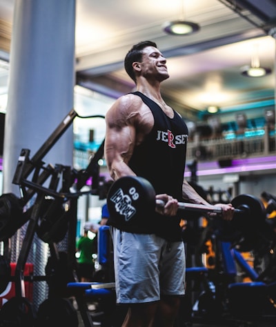 man in black tank top and blue pants holding black exercise equipment