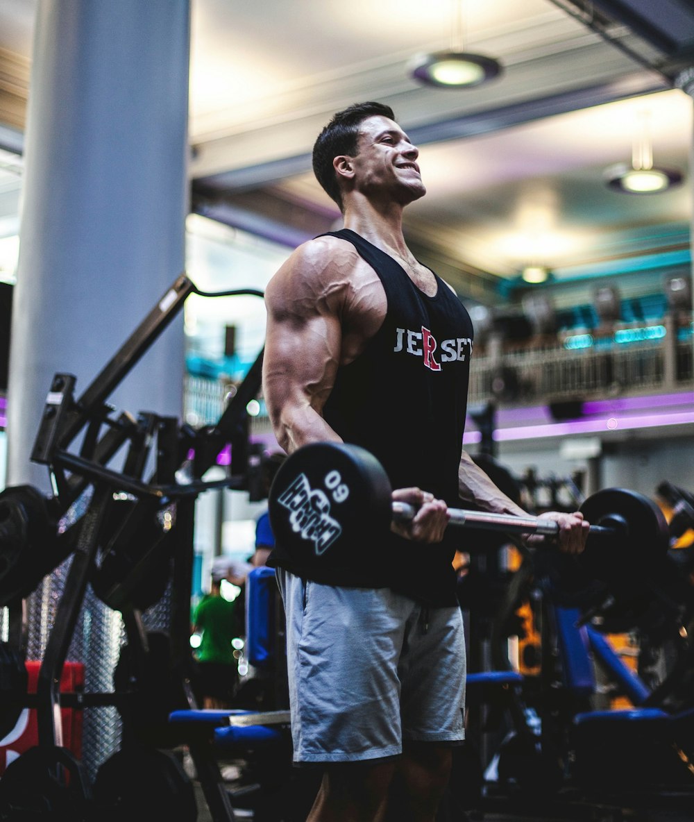 man in black tank top and blue pants holding black exercise equipment