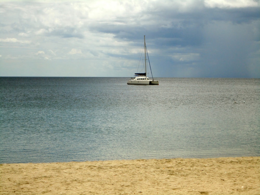 white sailboat on sea under white clouds and blue sky during daytime