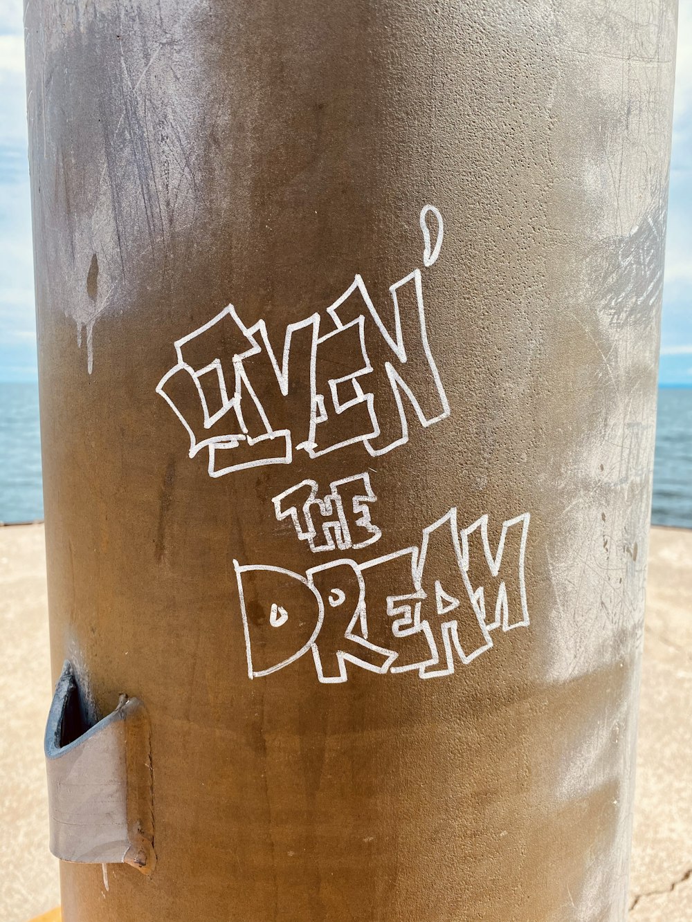 a pole with graffiti written on it near the ocean