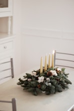 An elegant arrangement of candles and greenery on a minimalist wooden table.
