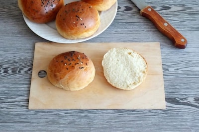 three brown bread on brown wooden chopping board buns zoom background