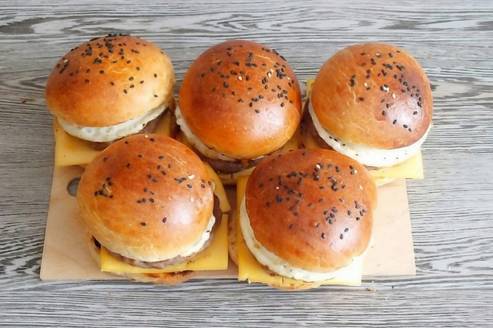 trois hamburgers sur assiette en céramique blanche