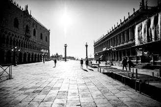 Wide-angle black and white image of Prague’s Old Town Square with its historic buildings and scattered early morning pedestrians.