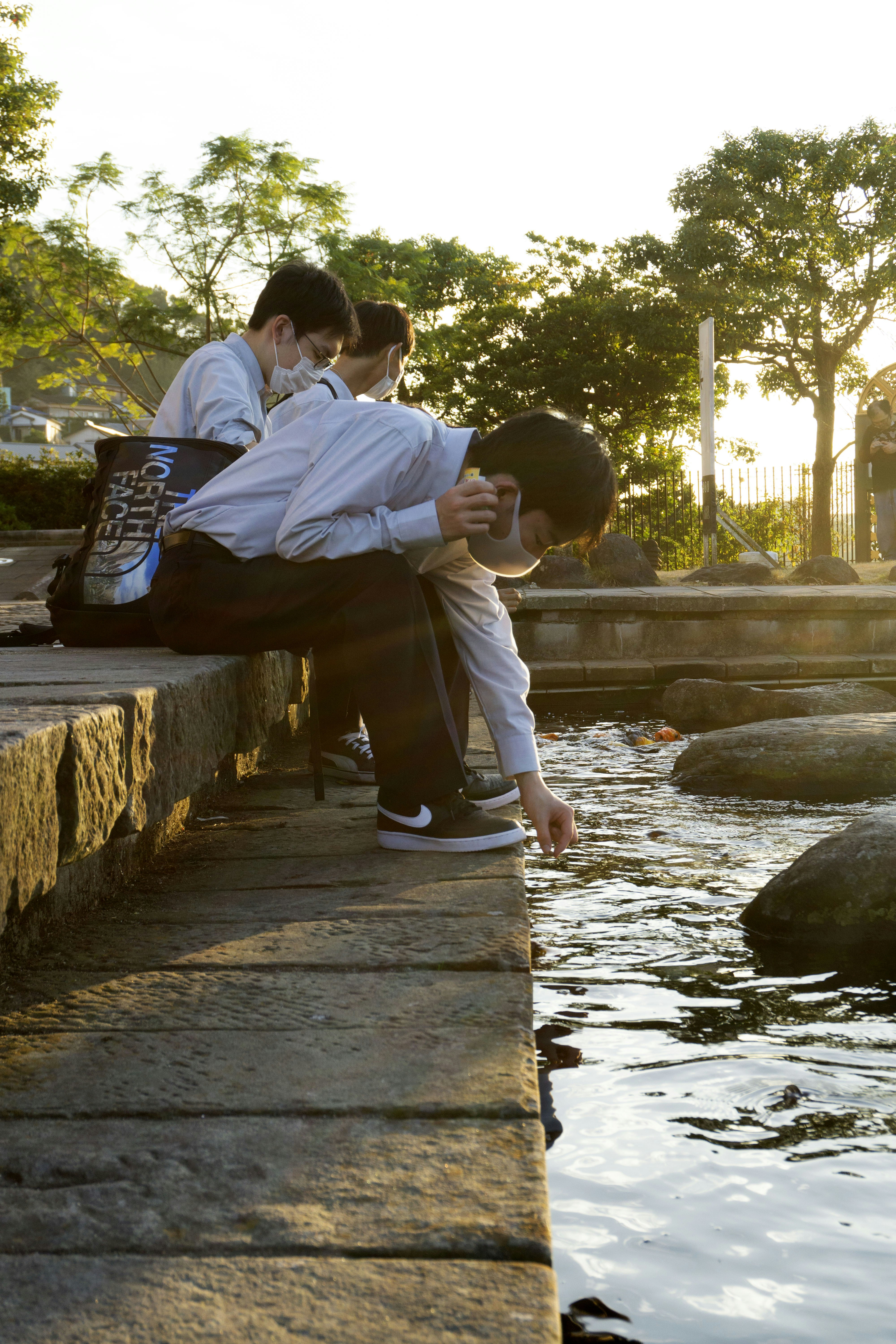 Japanese students feeding Koi fishes, in Nagasaki Glover Garden