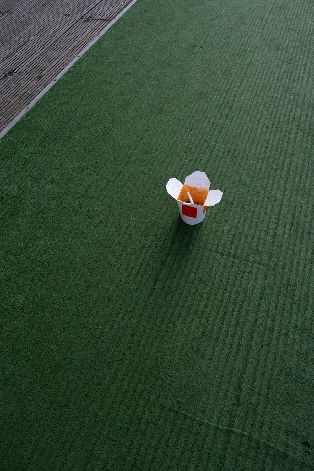 white and orange plastic cup on green textile