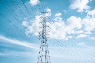black electric tower under blue sky and white clouds during daytime