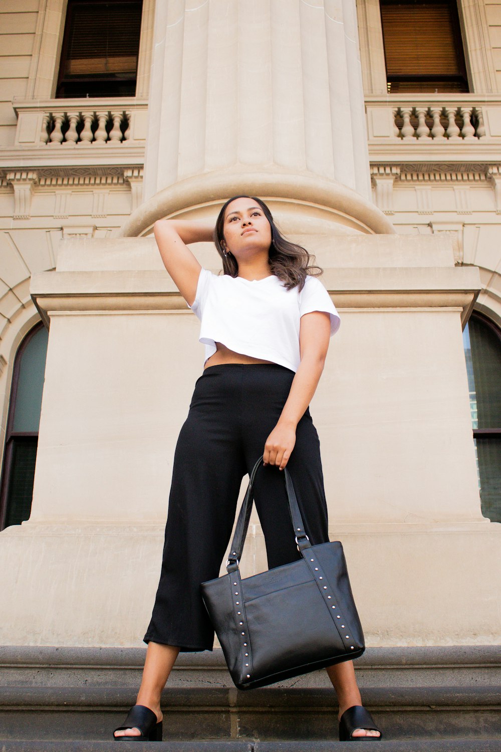 woman in white shirt and black skirt holding black leather handbag