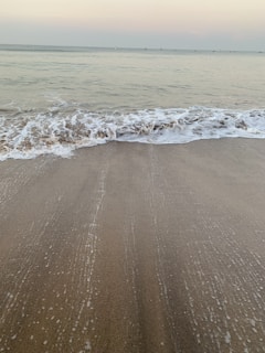 Gentle waves lapping on a quiet shore under a pastel sky at dusk.