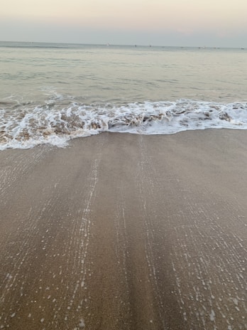 Gentle waves lapping on a quiet shore under a pastel sky at dusk.