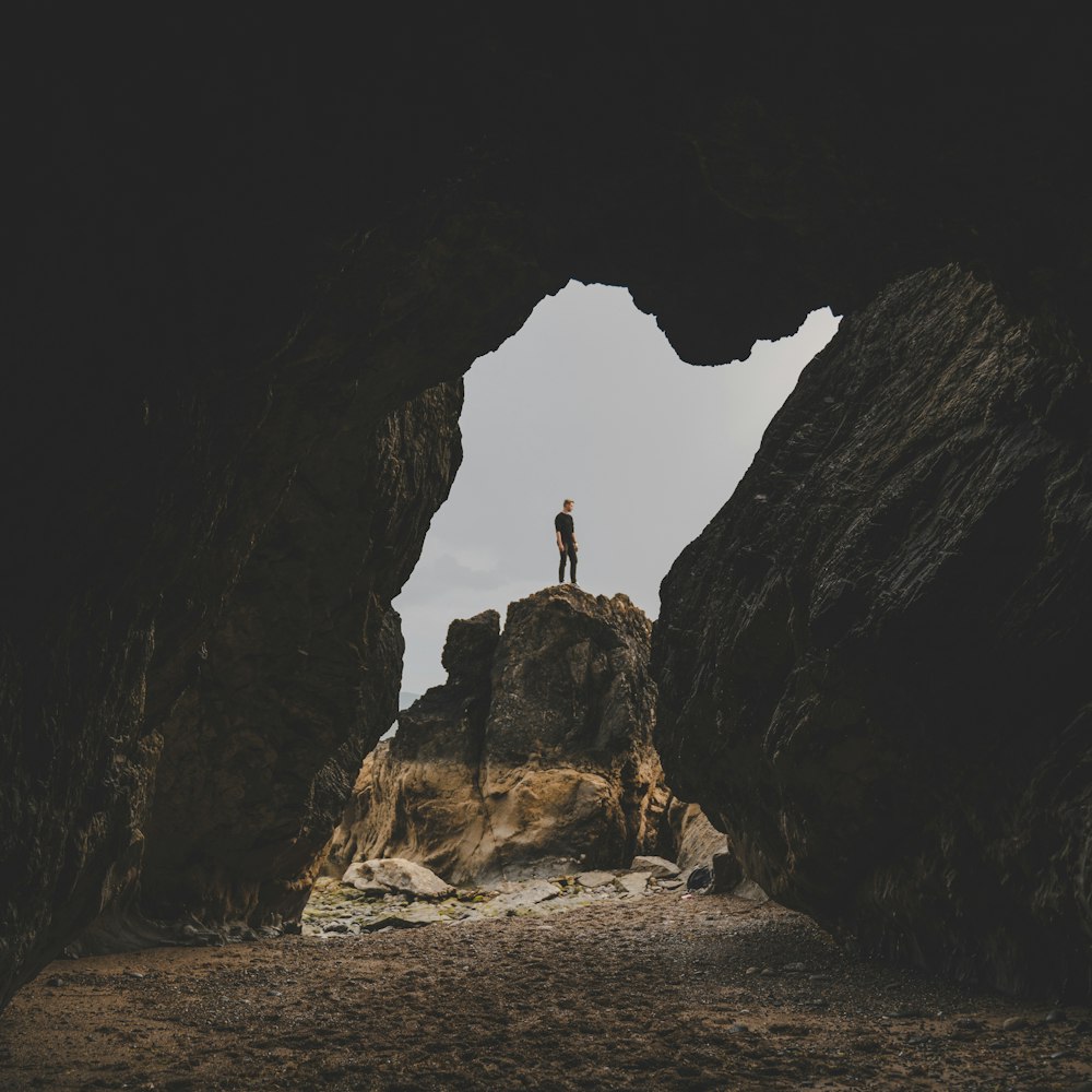 person in black shirt standing on rock formation during daytime