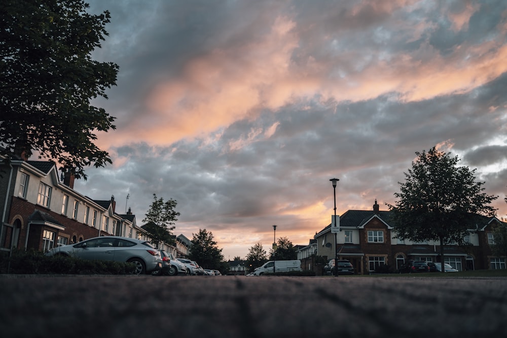 cars parked beside houses under cloudy sky during daytime