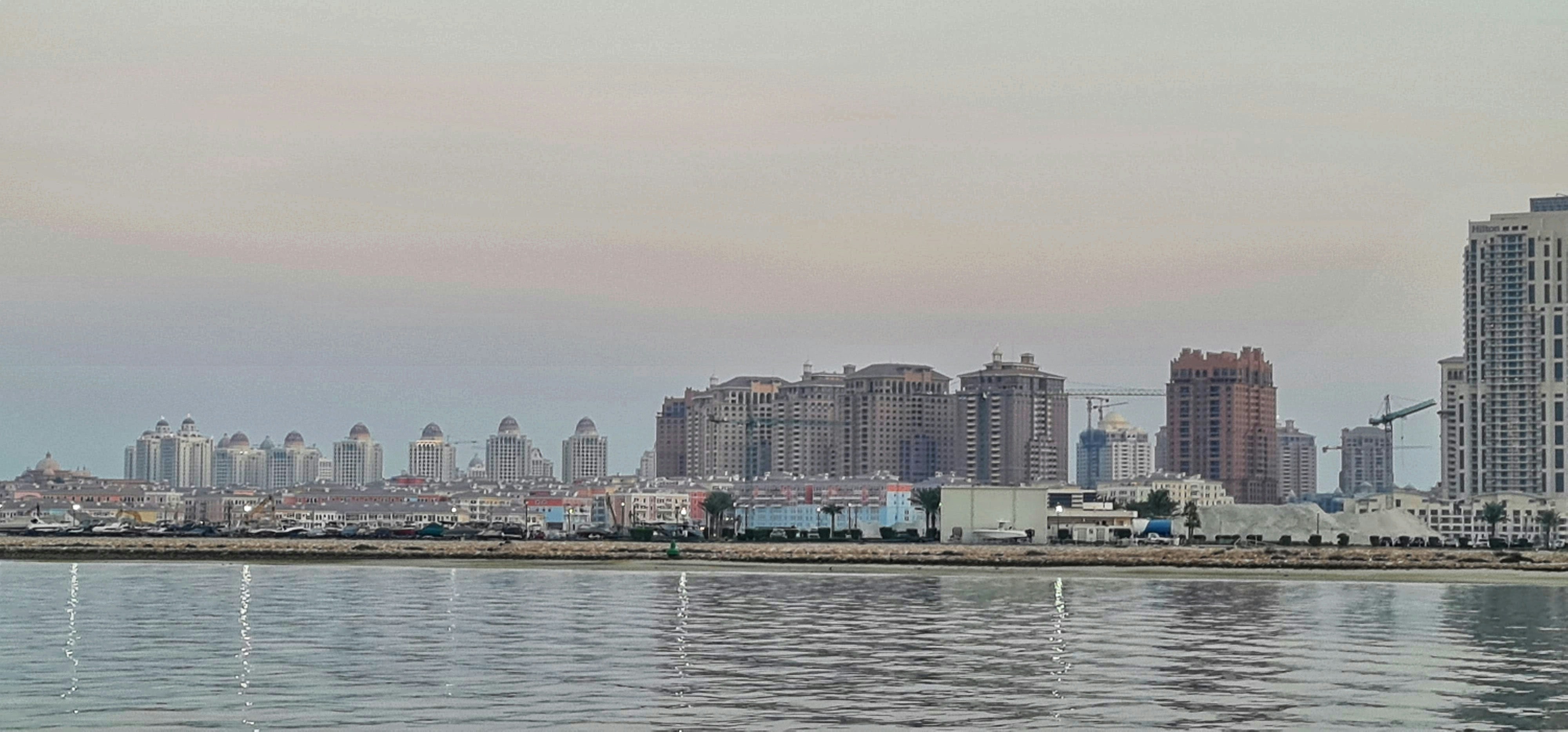 Modern apartment tower reflecting in Creek Harbour waterway with Dubai skyline