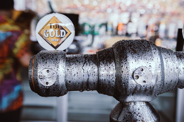 Close-up of a beer tap with bubbles rising, surrounded by gas cylinders in the background