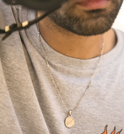 man in gray crew neck shirt wearing silver necklace