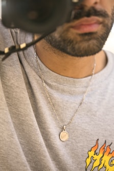man in gray crew neck shirt wearing silver necklace