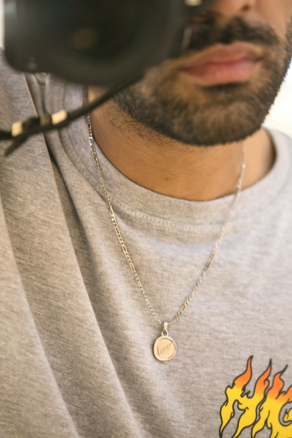 man in gray crew neck shirt wearing silver necklace