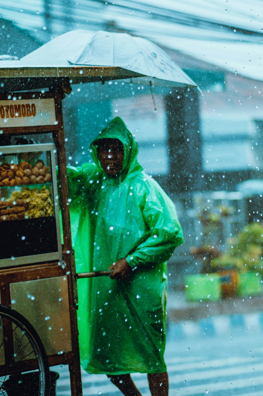 man in green hoodie standing near food stall during daytime