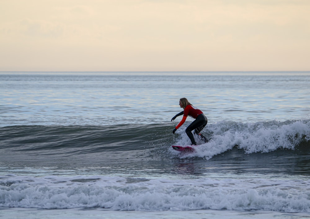 hombre con camisa roja surfeando en las olas del mar durante el día