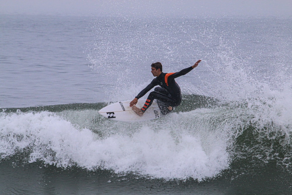 man in black and red wet suit surfing on sea waves during daytime