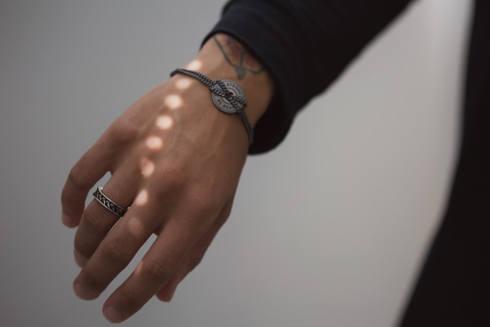 person wearing silver ring and silver bracelet