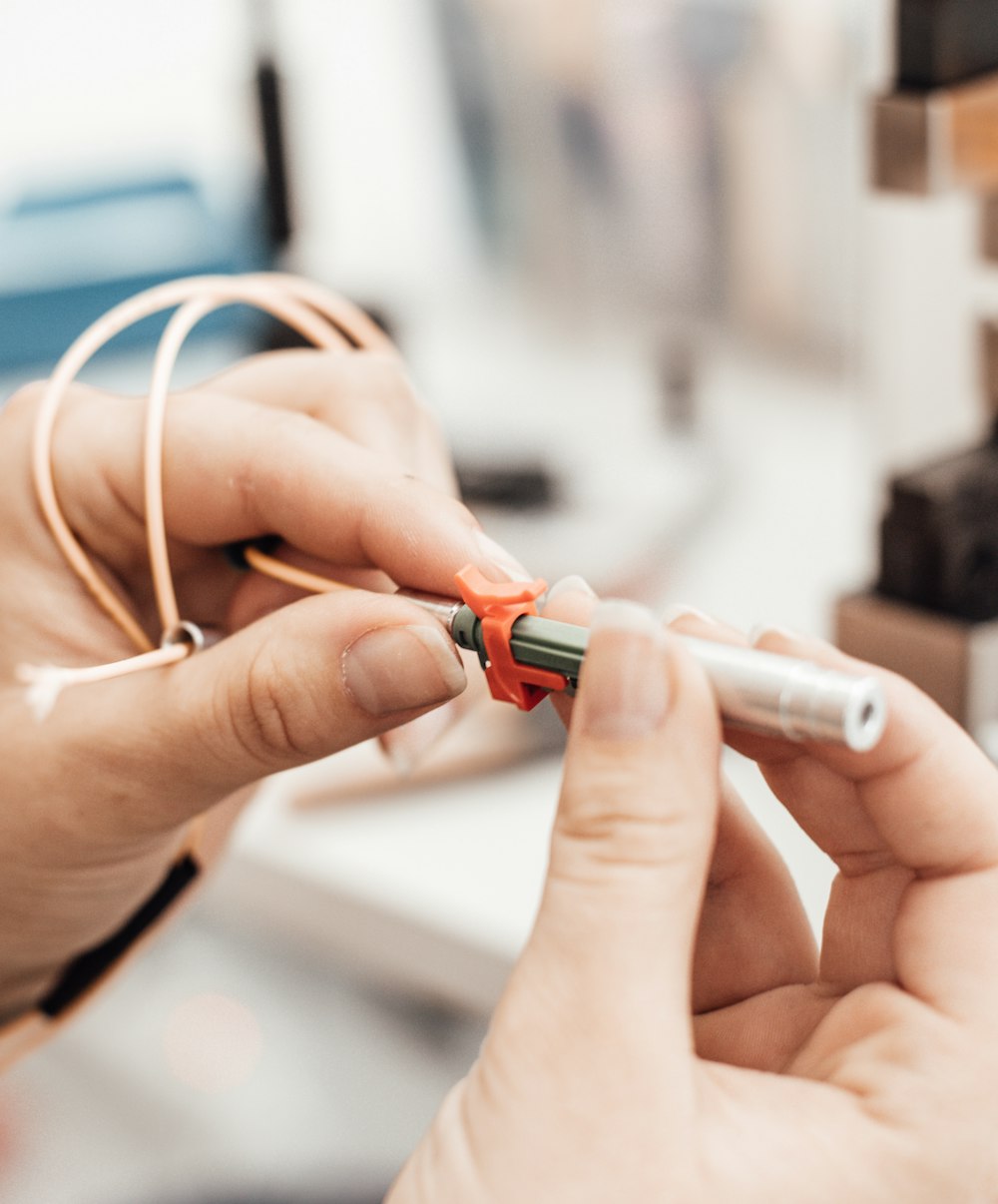 person holding red and white coated wire