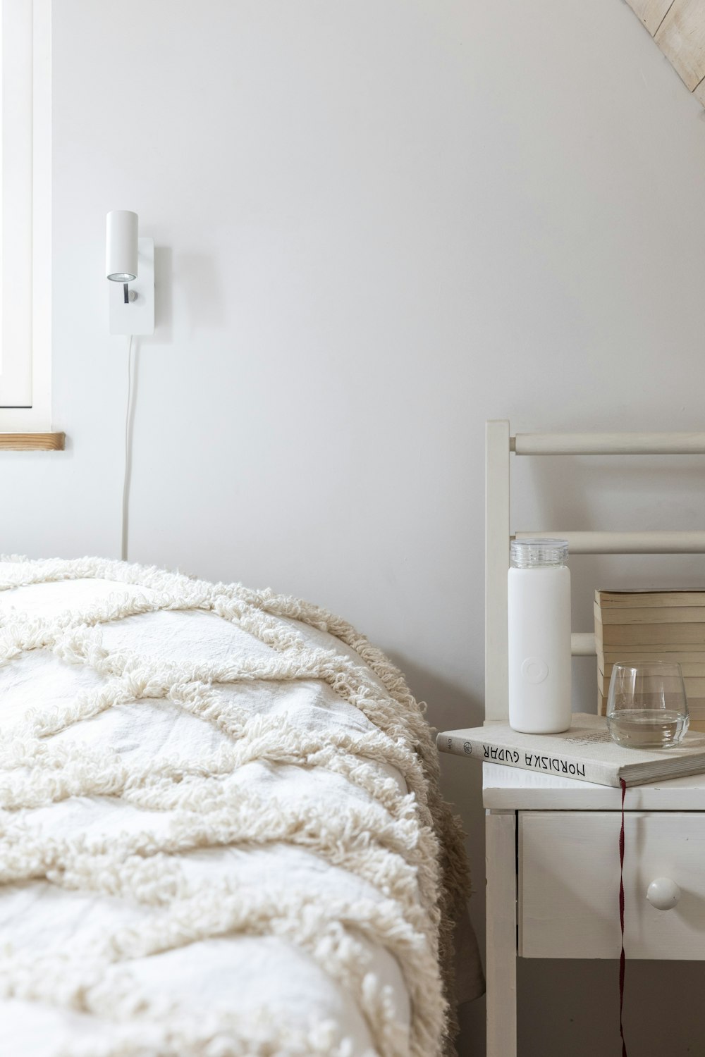 white bed linen near white wooden nightstand