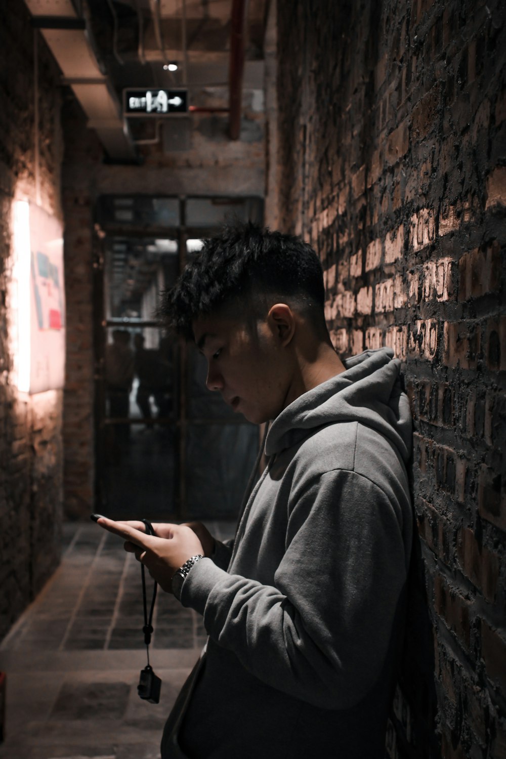 man in gray hoodie holding smartphone