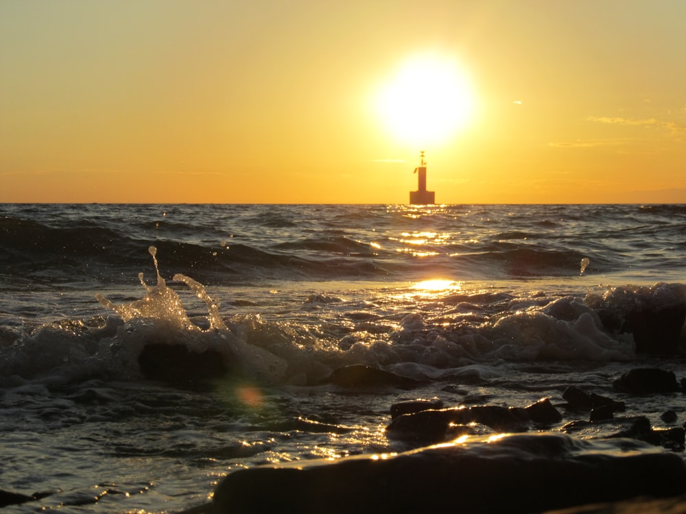 silhouette of person standing on rock formation near sea during sunset