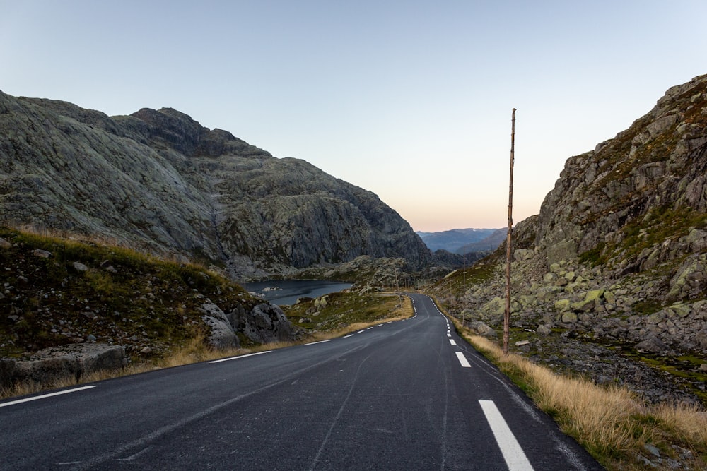 gray concrete road near green mountain during daytime