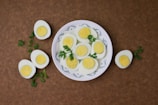 Close-up of perfectly boiled eggs nestled beside fresh-cut fruit on a rustic wooden plate.