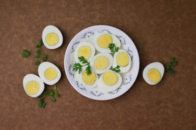 Boiled eggs sliced neatly on a plate with a sprinkle of spices.