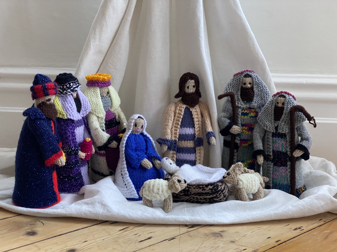 three white and blue knitted dolls on white textile, Nativity