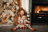 girl in red and white plaid pants sitting on floor beside brown and white floral sofa