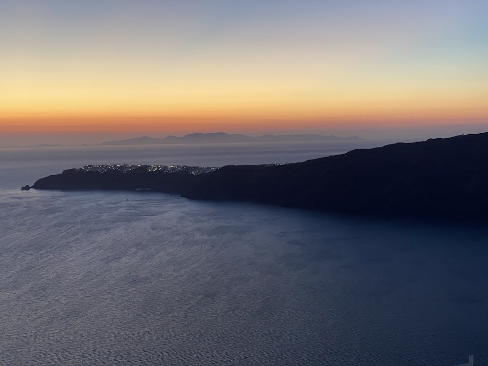 body of water near mountain during sunset