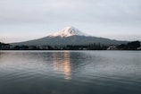 Snow-capped Mount Fuji reflected in a serene lake at dawn.