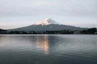 Mount Fuji towering over a calm lake, its reflection perfectly mirrored in the water.