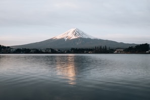 Snow-covered Mount Fuji reflected in the calm waters of a nearby lake