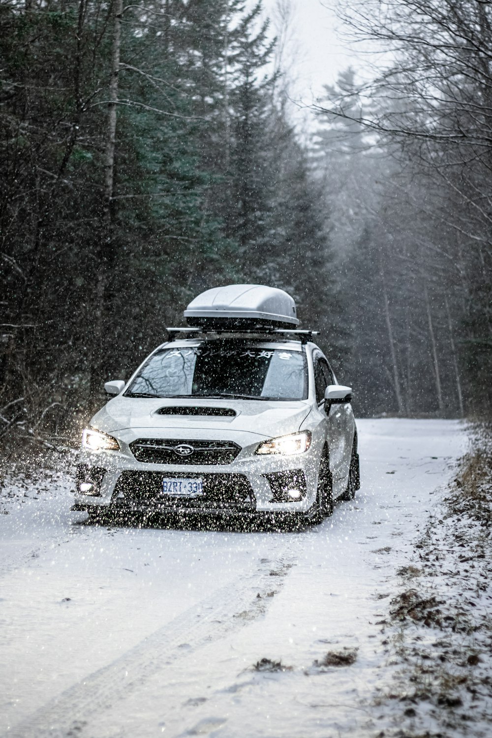 日中の雪に覆われた道路を走る黒いSUV