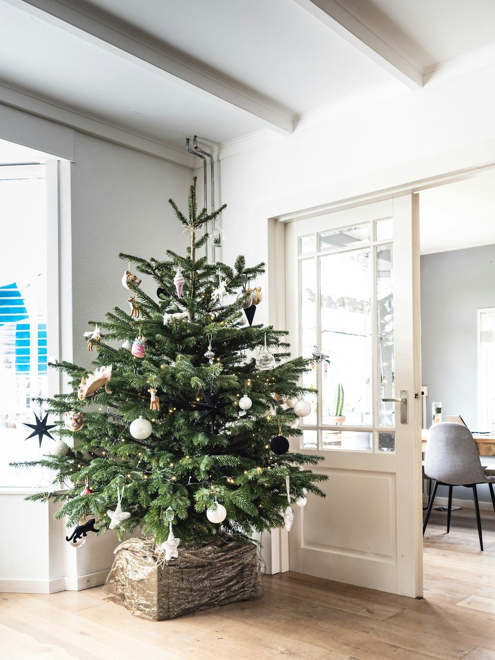 Sapin de Noël vert avec des boules de Noël près de la porte vitrée encadrée en bois blanc