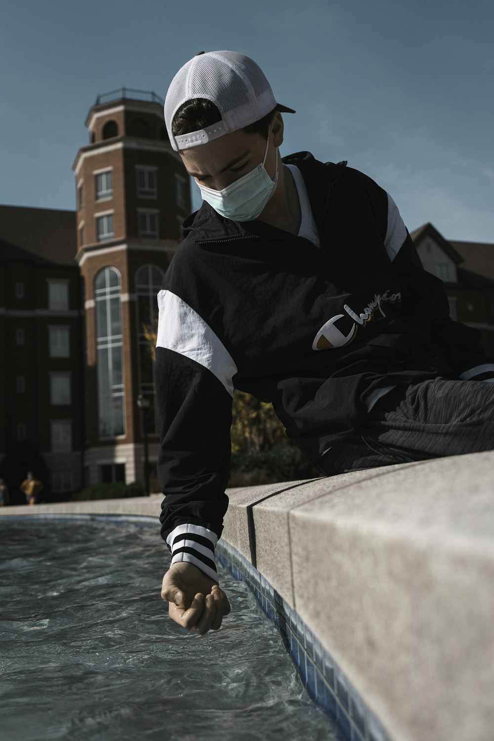 man in black and white jacket sitting on concrete bench during daytime