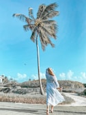 woman in white dress standing near palm tree during daytime